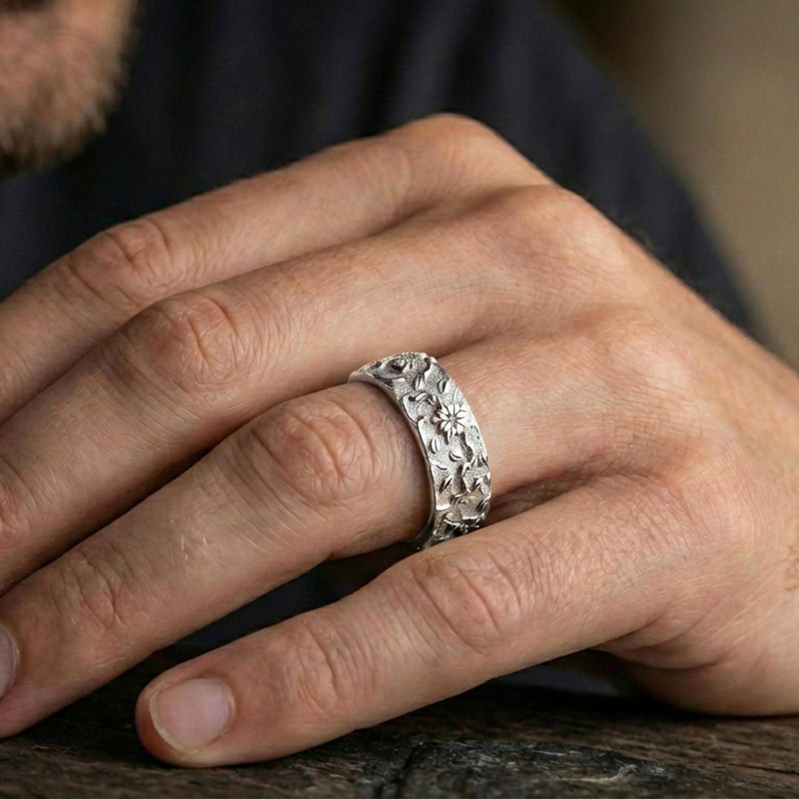 Polished silver floral engraved band ring worn on the finger, lifestyle image highlighting bright reflective finish, delicate flower carving, and everyday styling.