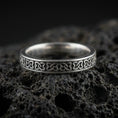 Load image into Gallery viewer, Oxidized sterling silver Celtic knot band ring on volcanic stone, macro close-up highlighting the repeating interlaced pattern and antique contrast.
