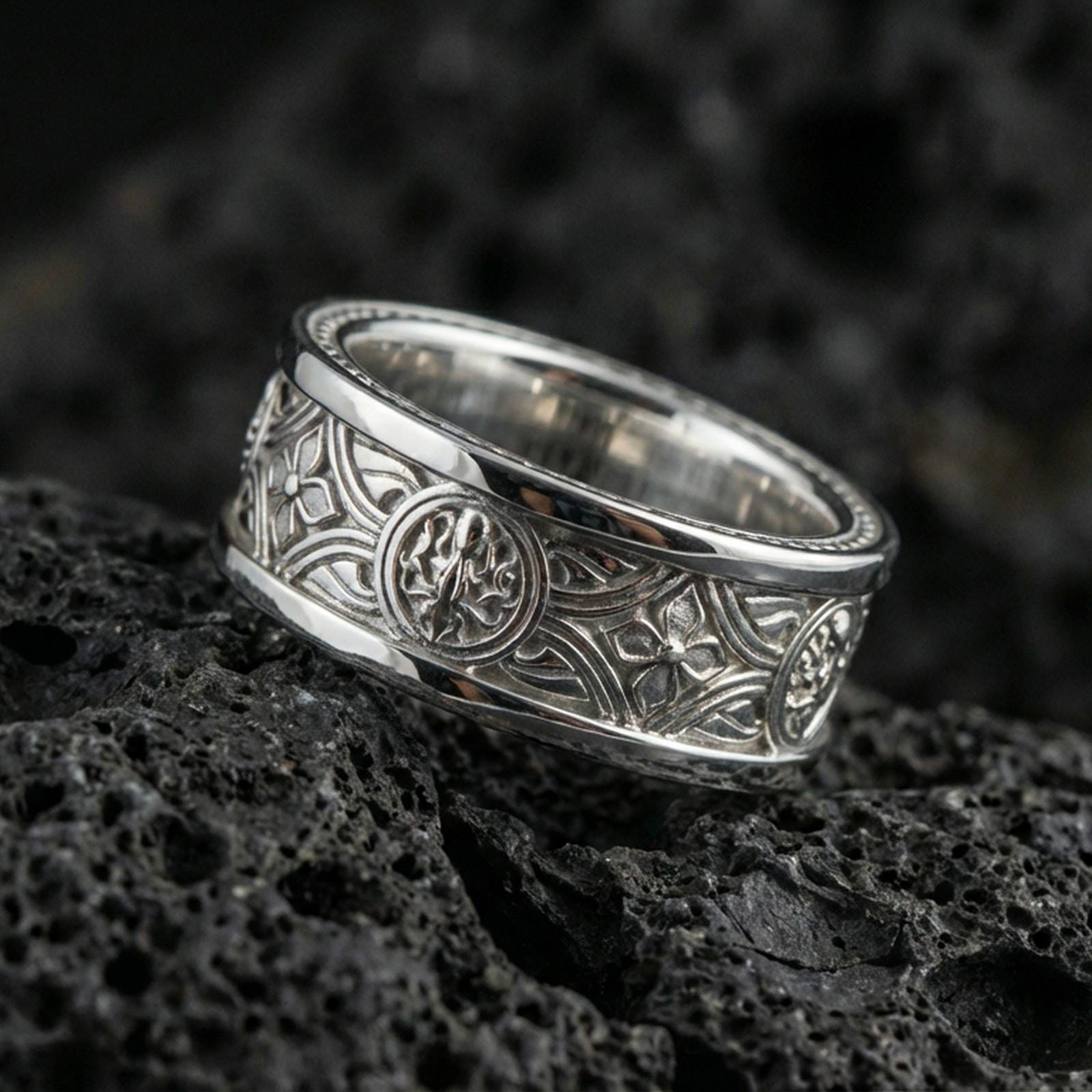 Polished silver spinner ring on volcanic stone, crisp macro photo emphasizing smooth edges, clean reflections, and sharp knotwork engraving depth.