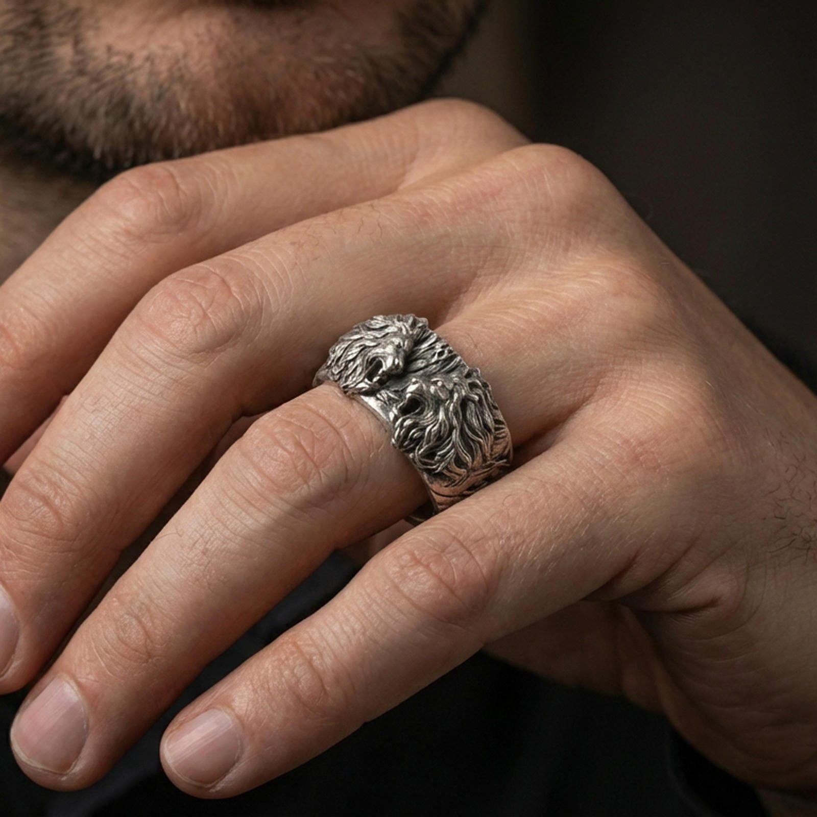 Oxidized sterling silver lion head ring worn on the finger, lifestyle image focusing on bold statement presence, antique depth, and masculine styling.