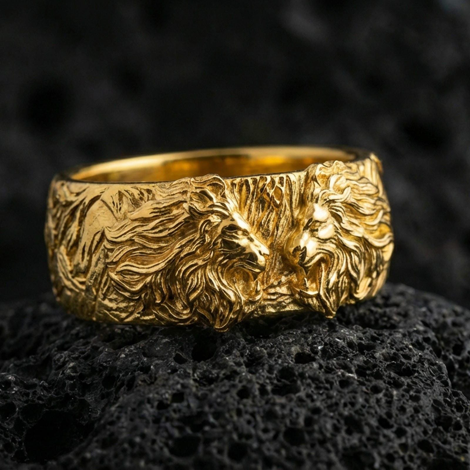 Gold plated lion head ring on volcanic stone, premium macro shot capturing warm gold tone across the lion relief and high-contrast engraved background.