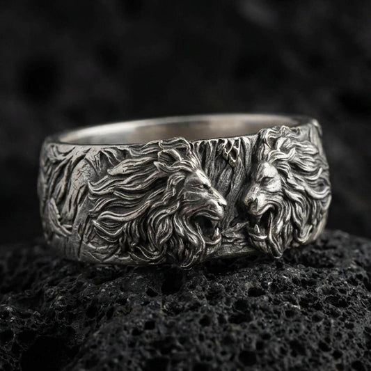 Oxidized sterling silver lion head ring on volcanic stone, macro close-up highlighting deep shadow contrast, roaring lion relief, and sculpted mane texture.