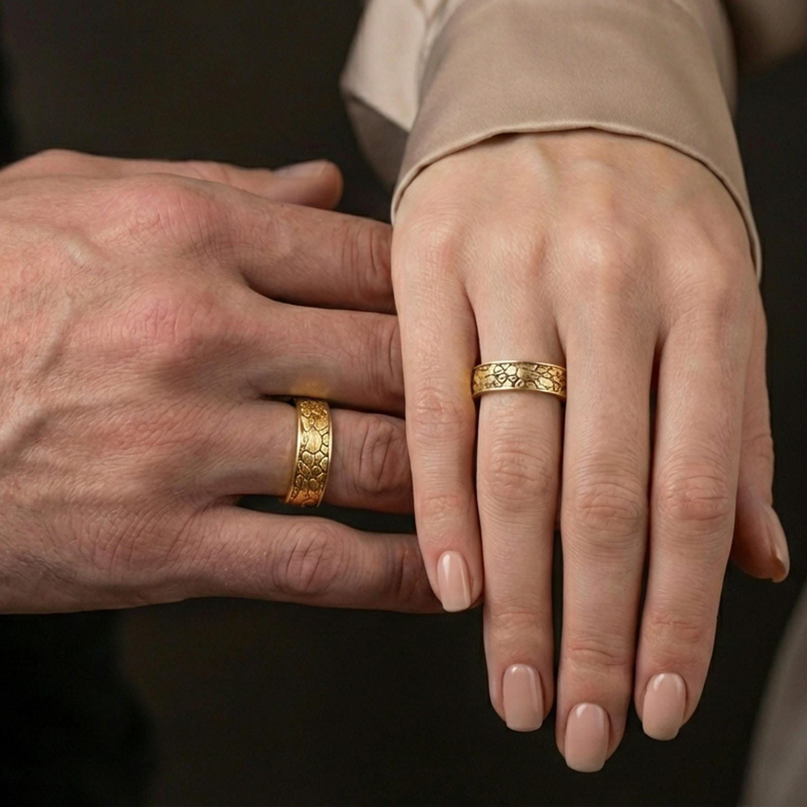 Gold plated pebble texture band ring worn on the finger, lifestyle photo emphasizing luxury warmth, unisex stacking potential, and statement texture.