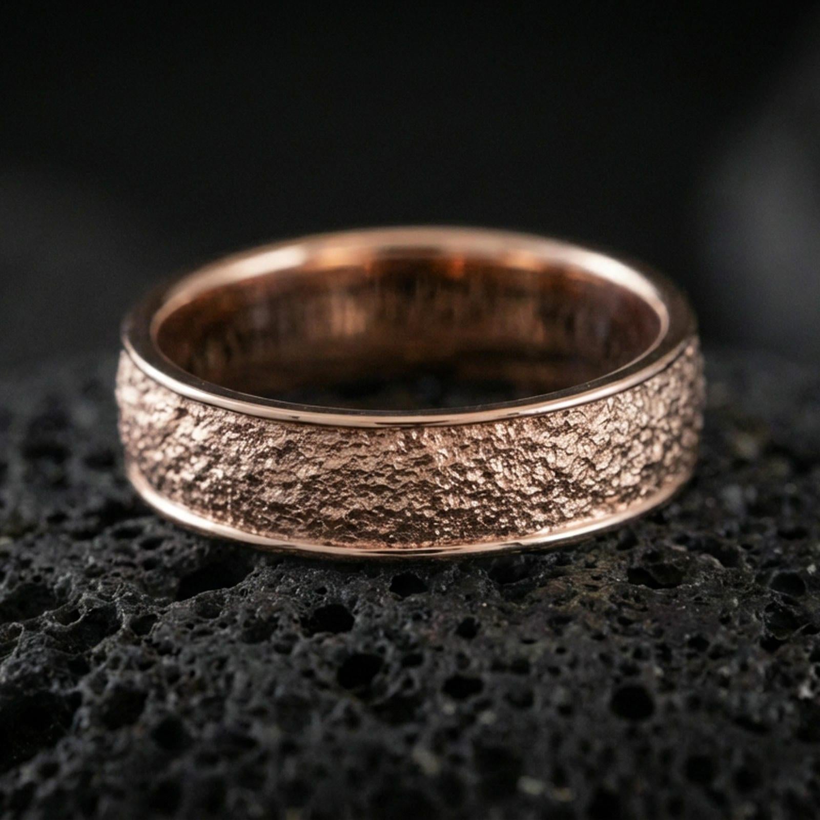 Rose gold plated bark texture band ring on volcanic stone, refined macro close-up showcasing soft rose sheen over the bark texture and smooth comfort edges.