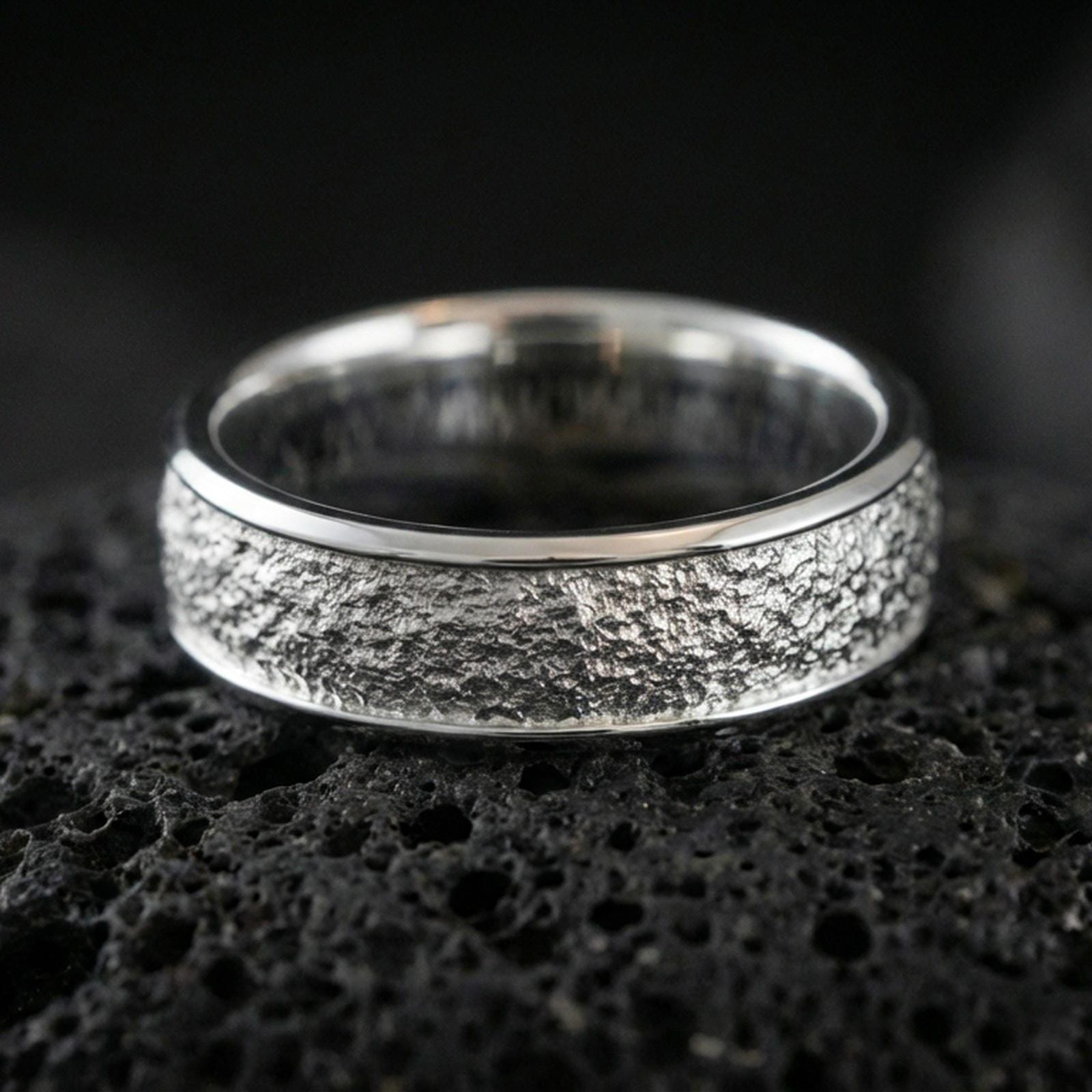 Polished silver bark texture band ring on volcanic stone, crisp macro photo emphasizing bright shine, clean edges, and organic bark-like texture detail.