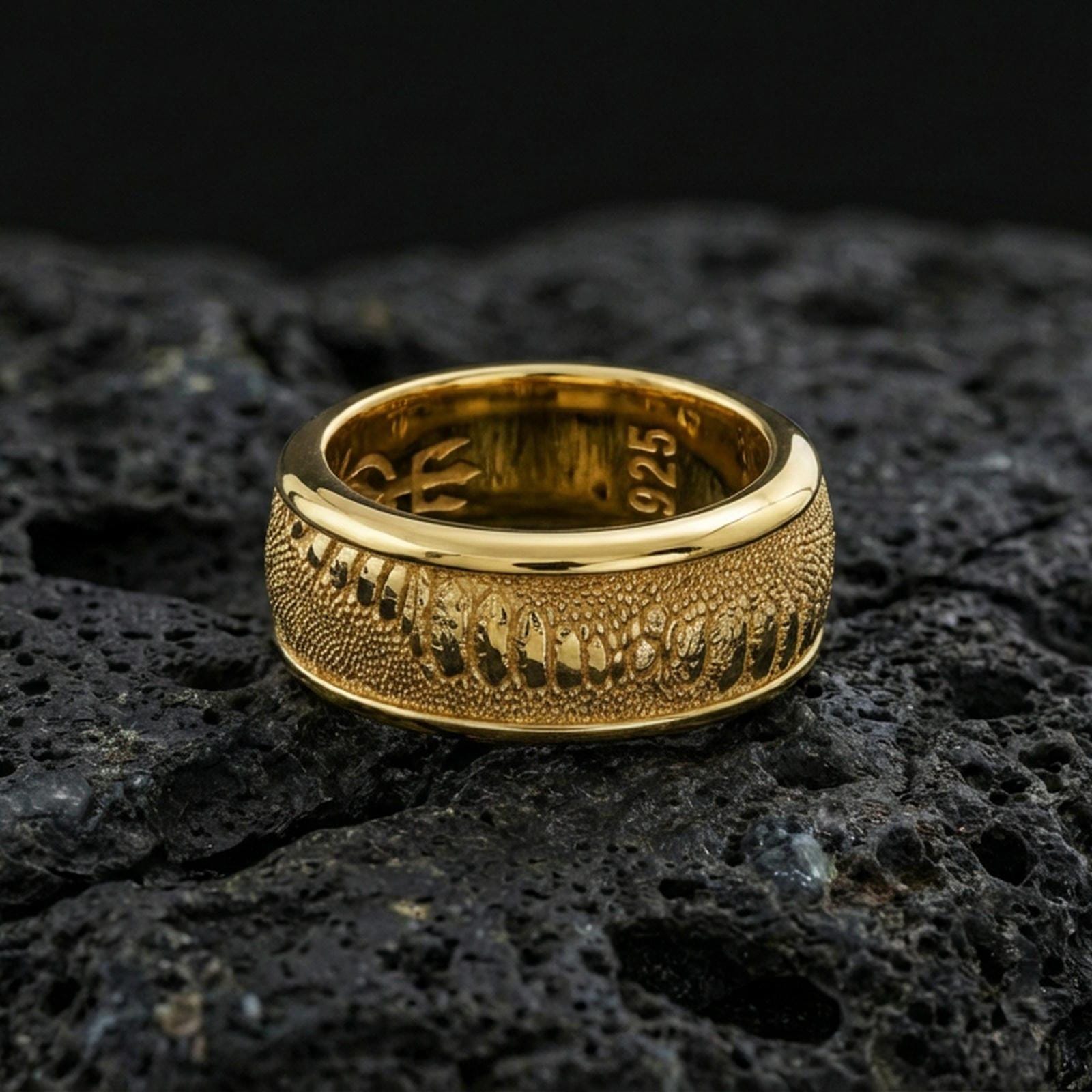 Gold plated lizard skin spinner ring on volcanic stone, premium macro shot capturing warm gold tone across the reptile texture with clear focus on the spinning layer.