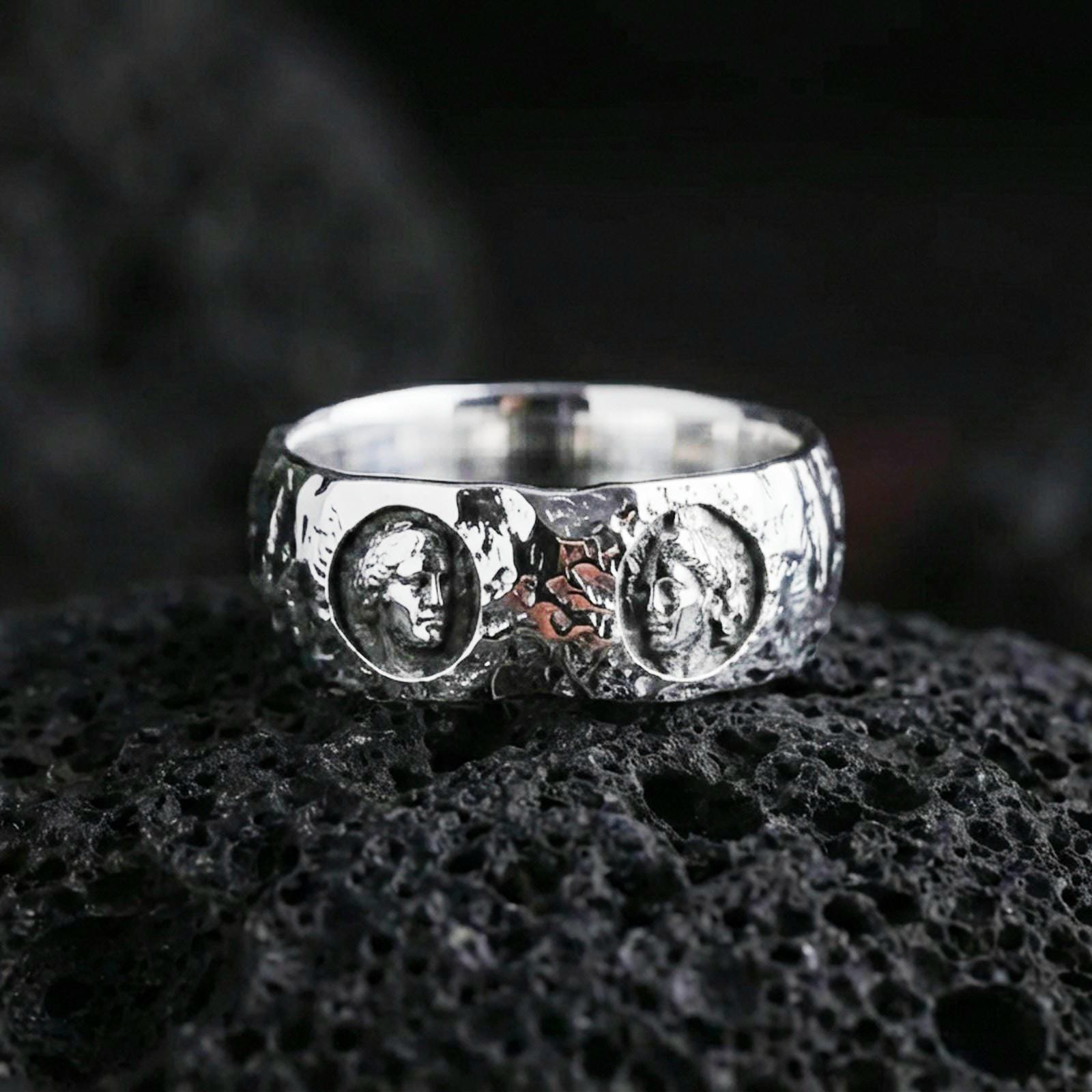 Polished silver Greek sculpture ring on volcanic stone, sharp macro shot emphasizing clean reflective edges, crisp cameo relief, and premium craftsmanship.