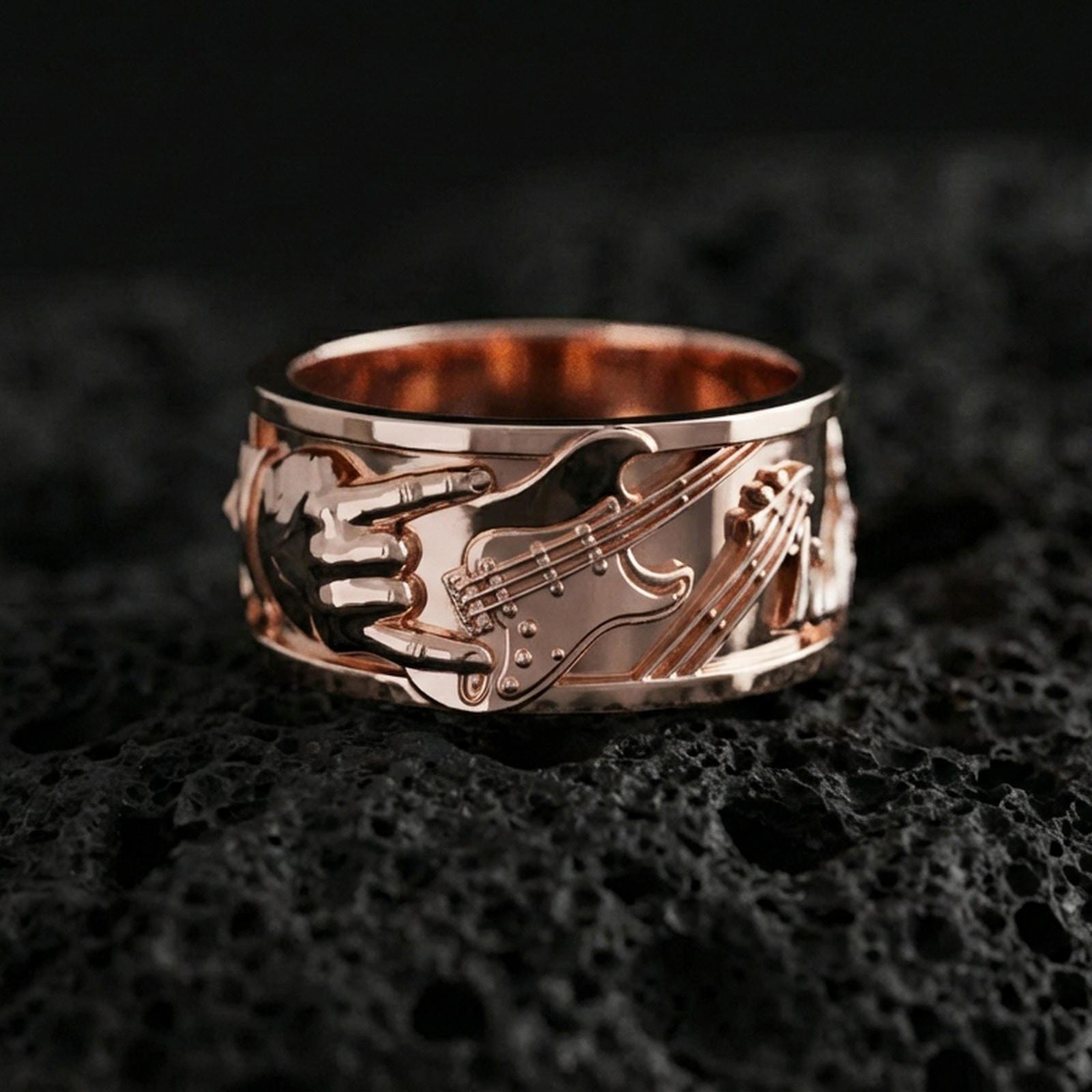 Rose gold plated guitar ring on volcanic stone, refined macro close-up showing soft rose warmth, high-relief guitar silhouette, and detailed engraving.