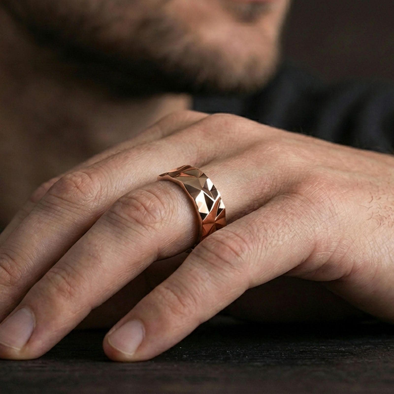 Rose gold plated faceted geometric band ring worn on the finger, lifestyle image highlighting elegant rose tone, faceted pattern, and refined contemporary styling.