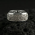 Load image into Gallery viewer, Polished silver cross scrollwork band ring on volcanic stone, crisp macro photo highlighting bright shine, clean edges, and symmetrical baroque engraving.
