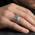 Load image into Gallery viewer, Oxidized sterling silver cross scrollwork band ring worn on the finger, lifestyle image presenting a bold gothic look with high-contrast engraved details.
