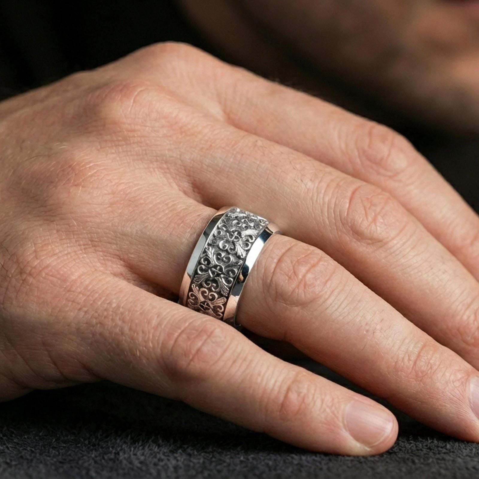 Polished silver cross scrollwork band ring worn on the finger, lifestyle photo featuring a sleek reflective finish and ornate cross pattern for daily statement wear.