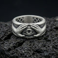 Load image into Gallery viewer, Oxidized sterling silver protective eye ring on volcanic stone, macro close-up highlighting darkened recesses, sculpted hands, and sharp eye relief.
