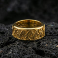 Load image into Gallery viewer, Rotating wave spinner ring on black volcanic stone, shown in a gold plated finish with warm shine accenting the ocean-wave relief across the spinner band.
