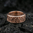 Load image into Gallery viewer, Rotating wave spinner ring on black volcanic stone, shown in a rose gold plated finish with a softer metallic glow that enhances the wave engraving depth.
