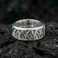 Load image into Gallery viewer, Rotating wave spinner ring on black volcanic stone, photographed in polished silver with clean highlights defining the curved wave lines and dotted texture.
