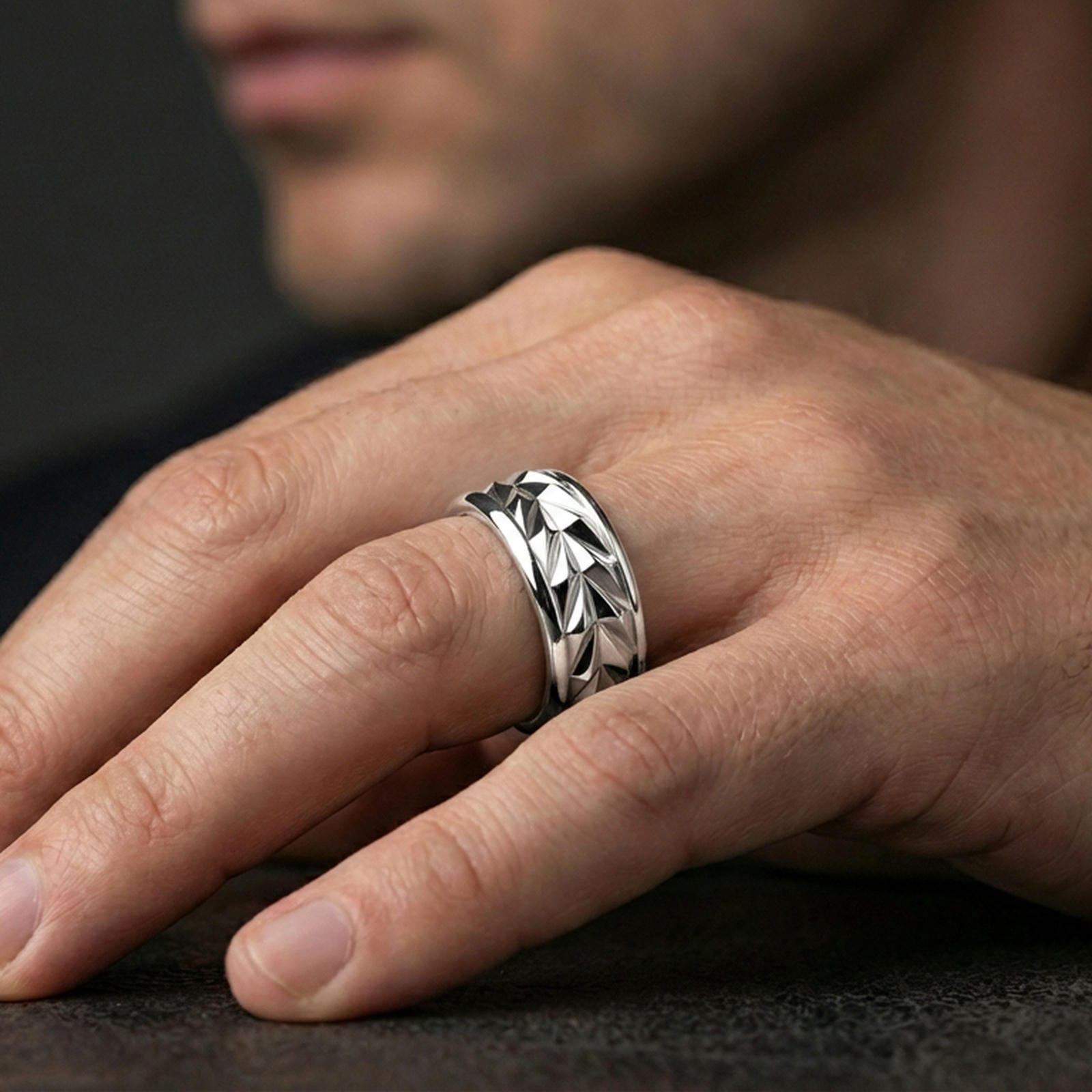 Mechanic style spinning fidget band ring worn on a finger, polished silver look with crisp highlights emphasizing the rotating faceted surface.