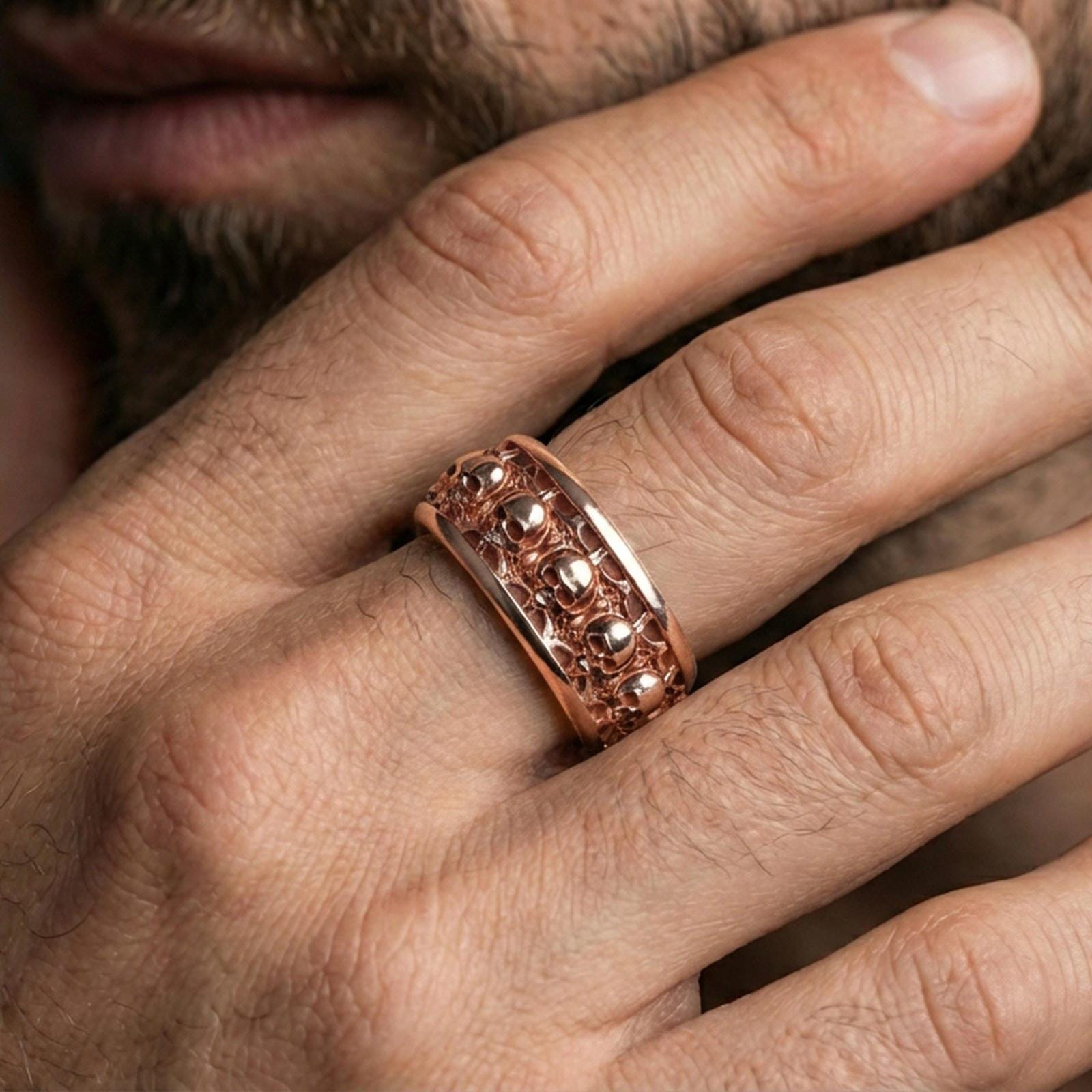 Skull motif sterling silver band ring worn on a finger, rose gold plated look with refined warmth and clear definition in the skull pattern.