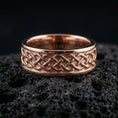Load image into Gallery viewer, Sterling silver Celtic knot band ring on black volcanic stone, presented in a rose gold plated finish with a softer warm tone that complements the knotwork depth and borders.
