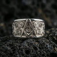 Load image into Gallery viewer, Sterling silver Masonic square and compass band ring on black volcanic stone, shown in a polished silver look with crisp reflections across the square, compass, and decorative scrollwork.
