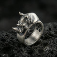 Load image into Gallery viewer, Sterling silver rhino head ring photographed on black volcanic stone, featuring an oxidized finish that deepens the shadows in the sculpted horn and facial lines.
