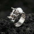 Load image into Gallery viewer, Sterling silver rhino head ring photographed on black volcanic stone, shown in a polished silver finish with clean highlights across the horn, snout, and smooth band.
