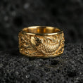 Load image into Gallery viewer, Koi fish spinner band ring on black volcanic stone, shown in a gold plated finish with warm shine emphasizing the swirling water details.
