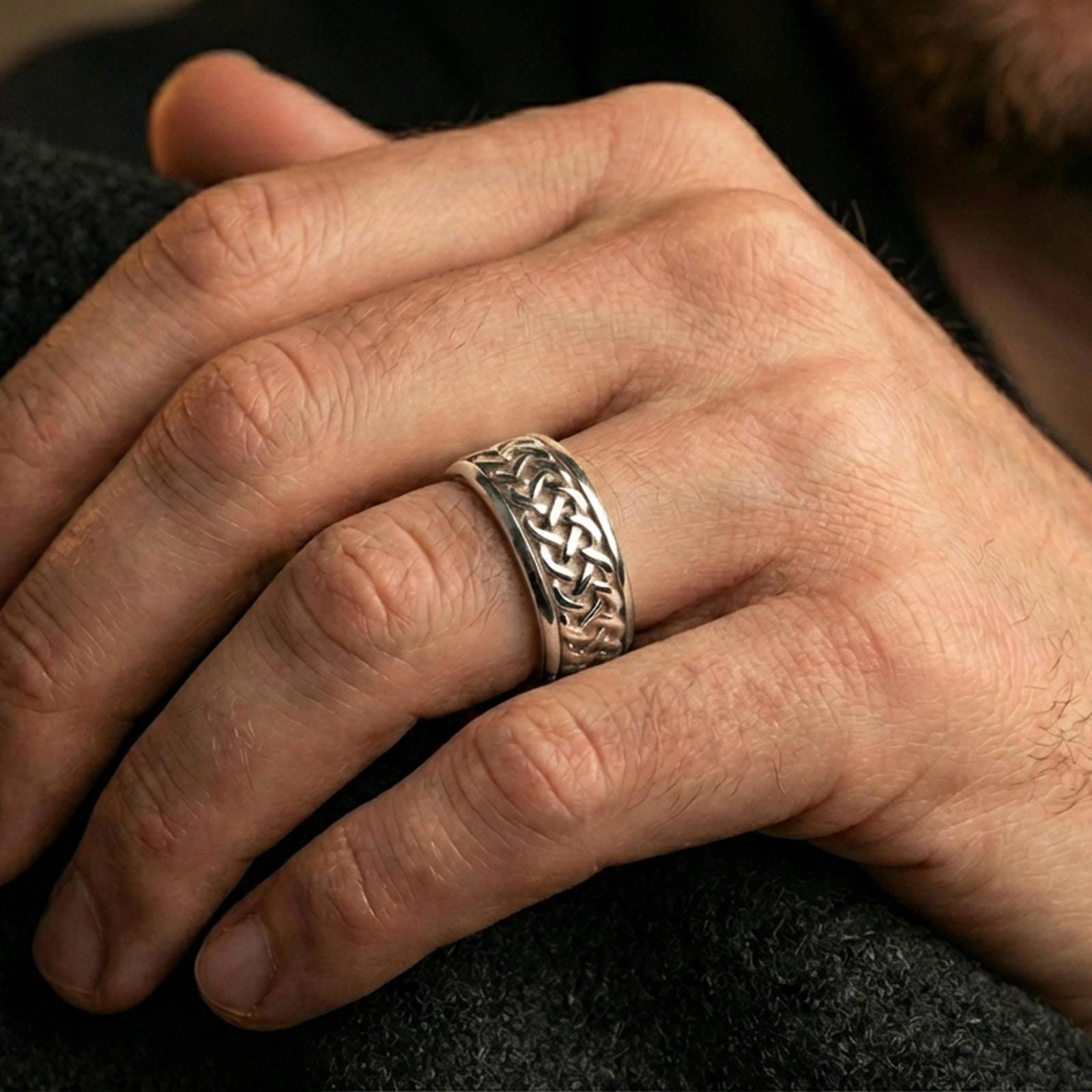 Celtic knot spinner band ring worn on a finger, polished silver finish with clean highlights and a modern, refined look.