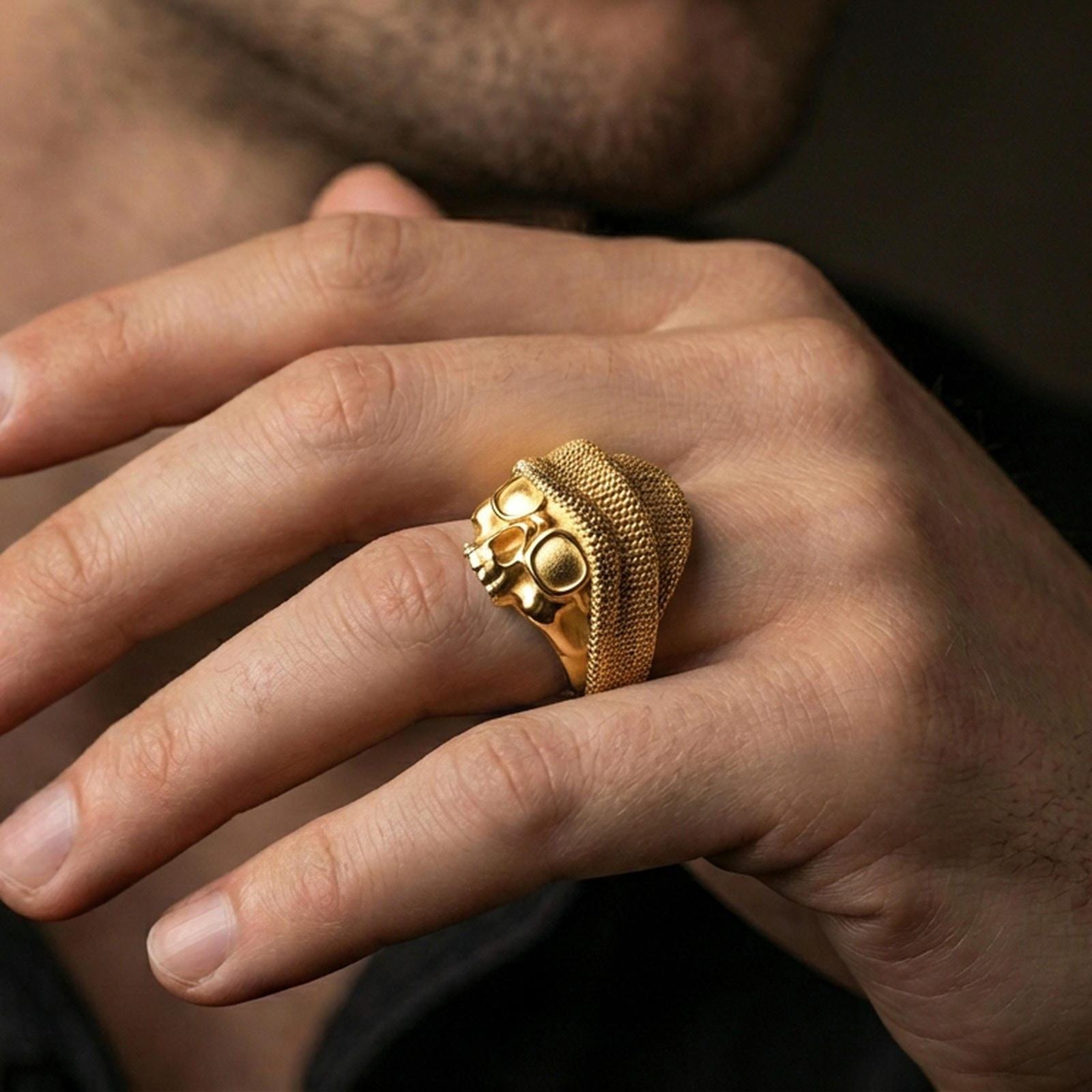 Gold plated skull beanie ring worn on a finger, lifestyle image emphasizing the bright metal tone and high-relief skull face