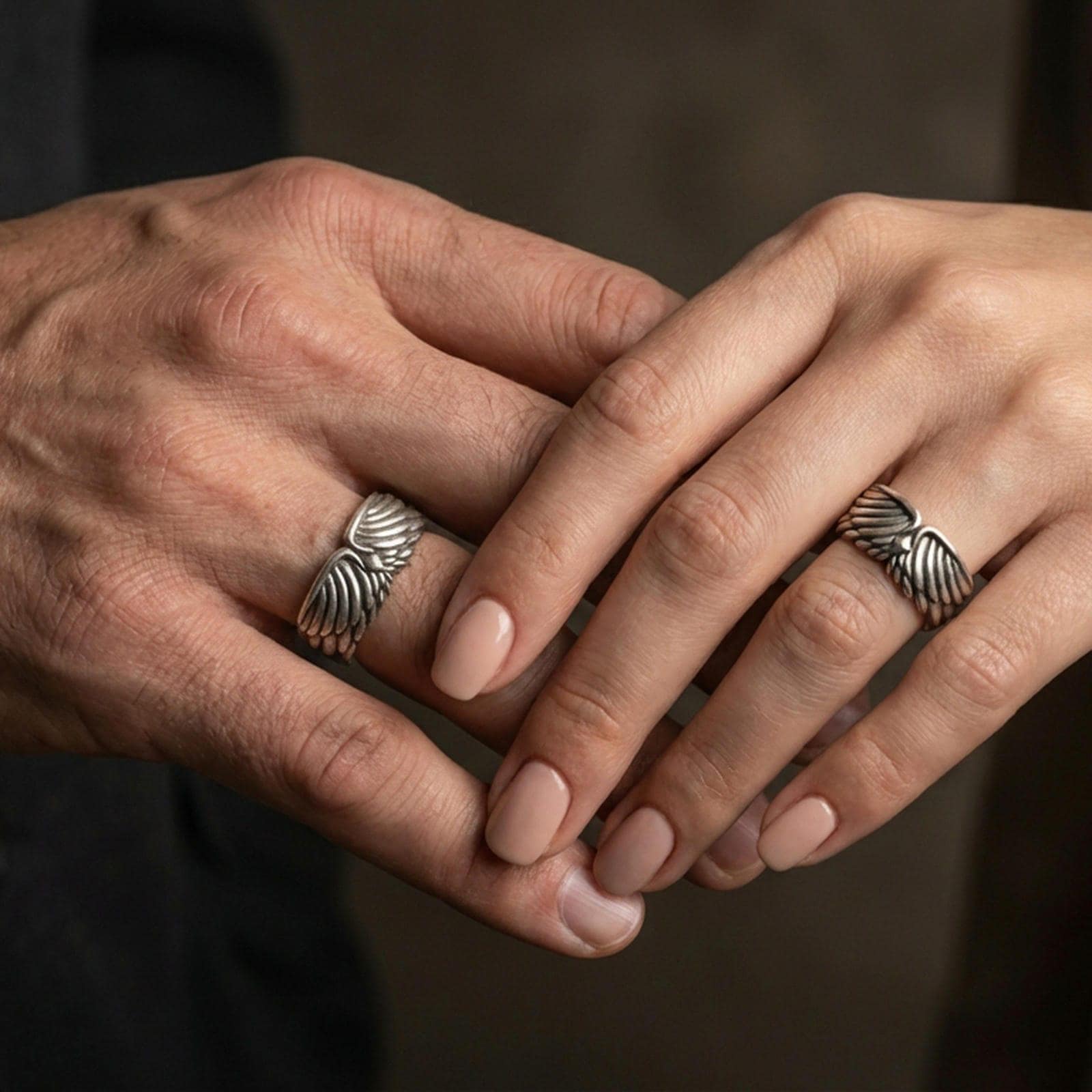 Angel wing sterling silver band ring worn on a finger of a woman and man, oxidized finish creating a bold vintage look and clear feather definition.