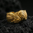 Load image into Gallery viewer, Eagle head and wing sterling silver ring on black volcanic stone, shown in a gold plated finish with warm reflections emphasizing the sculpted feather layers.
