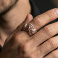 Load image into Gallery viewer, Eagle head and wing sterling silver ring worn on a finger, rose gold plated finish adding elegant warmth while keeping the eagle relief clear.
