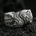 Load image into Gallery viewer, Eagle head and wing sterling silver ring on black volcanic stone, shown with an oxidized finish that deepens the feather grooves and facial relief.
