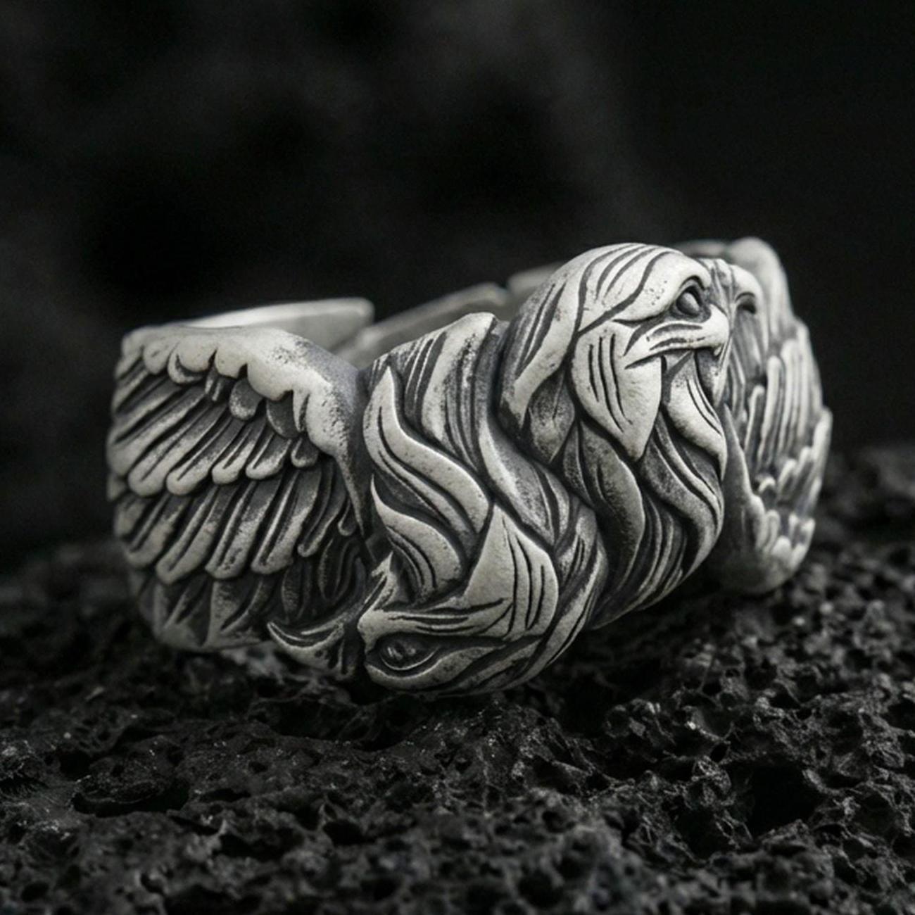 Eagle head and wing sterling silver ring on black volcanic stone, shown with an oxidized finish that deepens the feather grooves and facial relief.