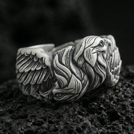 Eagle head and wing sterling silver ring on black volcanic stone, shown with an oxidized finish that deepens the feather grooves and facial relief.