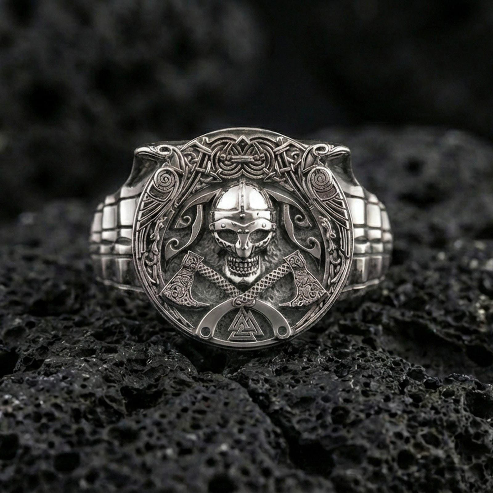 Polished silver Norse warrior signet ring on porous volcanic stone, close-up highlighting crisp rune-inspired linework, helmet skull and axe detailing