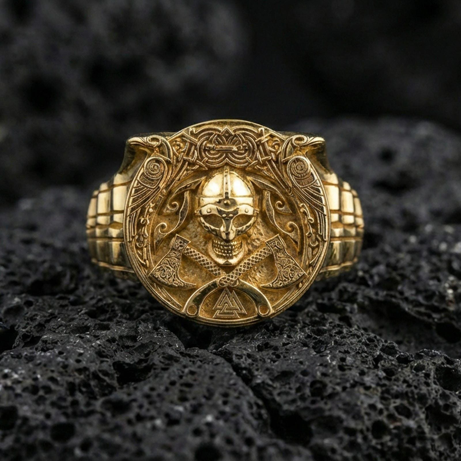 Gold plated Viking helmet and crossed axes ring on volcanic rock, premium macro photo emphasizing high-contrast carvings and bold shield-like face