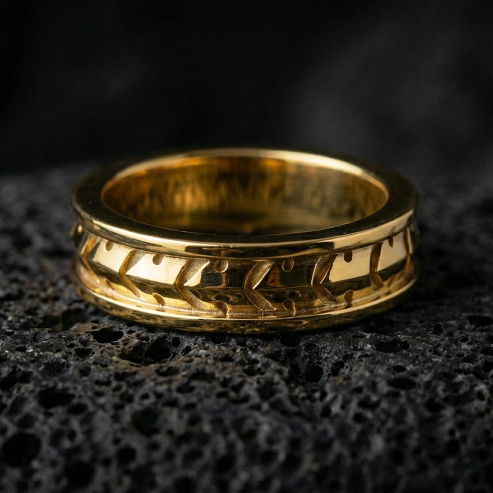 Industrial tread pattern sterling silver spinner ring on black volcanic stone, shown in a gold plated finish with warm highlights outlining the tire-tread geometry.