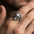 Load image into Gallery viewer, Oxidized laurel wreath skull ring worn on a finger, lifestyle close-up showing bold gothic face, leaf crown band and darkened recessed details
