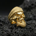 Load image into Gallery viewer, Gold plated skull ring with beret and detailed beard on volcanic rock, premium macro photo emphasizing warm tone, sharp facial contours and relief carving
