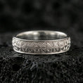 Load image into Gallery viewer, Polished silver wedding band on black volcanic stone, crisp starburst flower engraving, centered close-up studio lighting.
