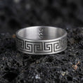 Load image into Gallery viewer, Oxidized sterling silver Greek key band ring on dark volcanic rock, bold meander pattern engraving, premium macro product shot.
