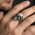 Load image into Gallery viewer, Oxidized skull biker ring worn on a finger, lifestyle close-up showing skeletal claw hand grip, deep darkened recesses and aggressive gothic statement look
