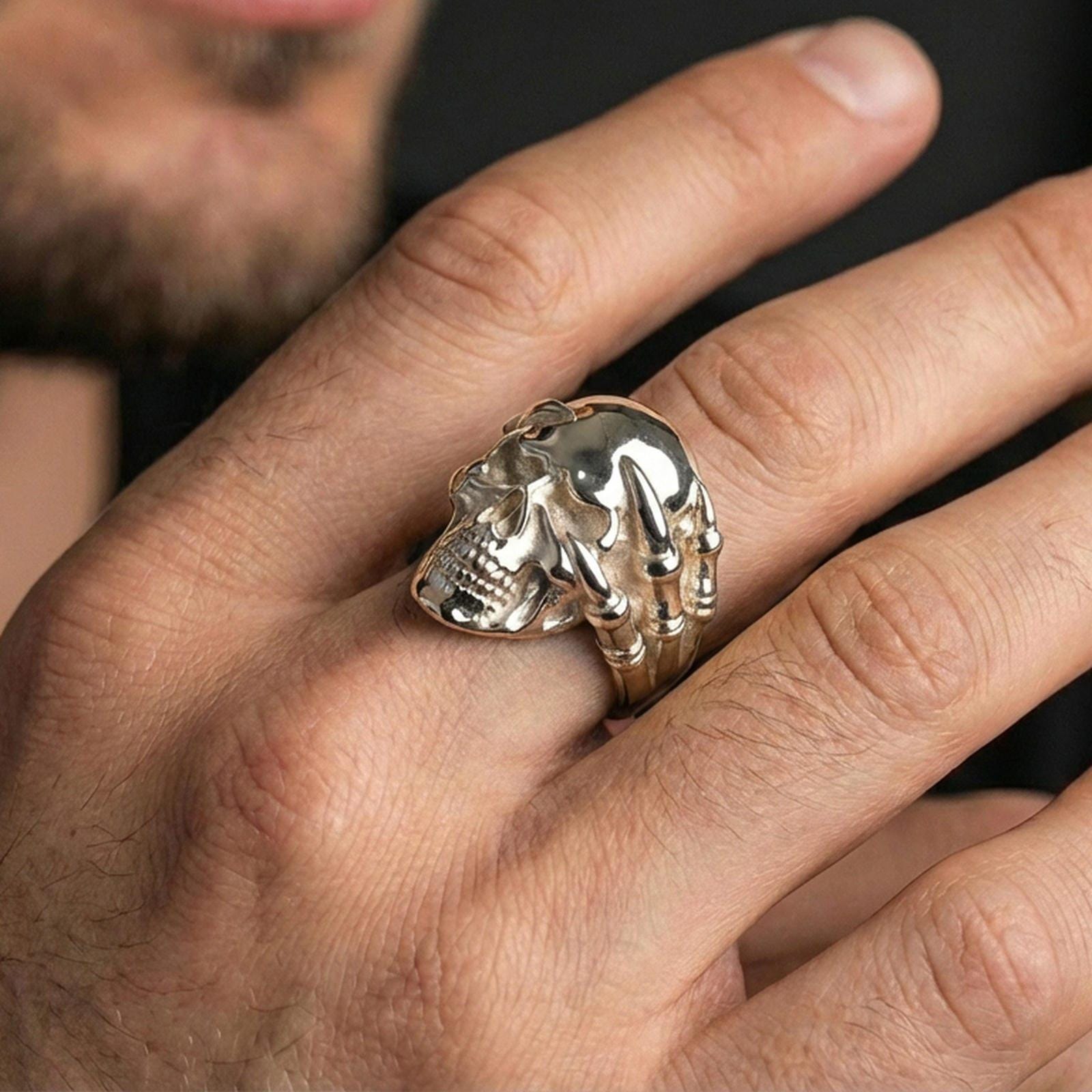Polished silver skull ring with claw hand worn on the finger, wearable shot highlighting clean shine, sharp skull teeth and sculpted bone fingers