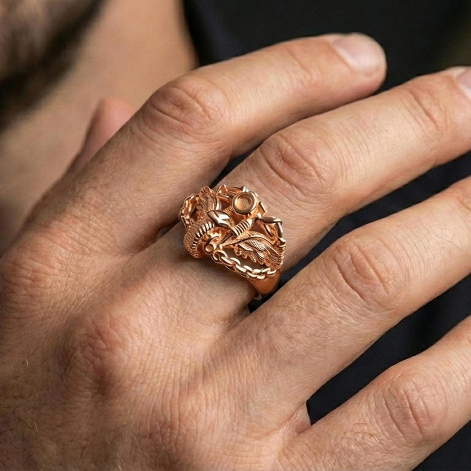 Rose gold plated winged motorcycle ring worn on a finger, close-up lifestyle photo showcasing warm finish, chain band texture and detailed sculpted bike design