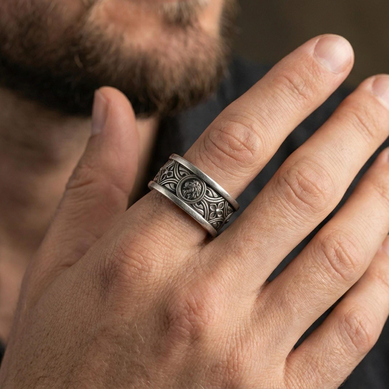 Oxidized sterling silver lion medallion band worn on finger, raised lion relief with ornate pattern detail, natural lifestyle hand shot.