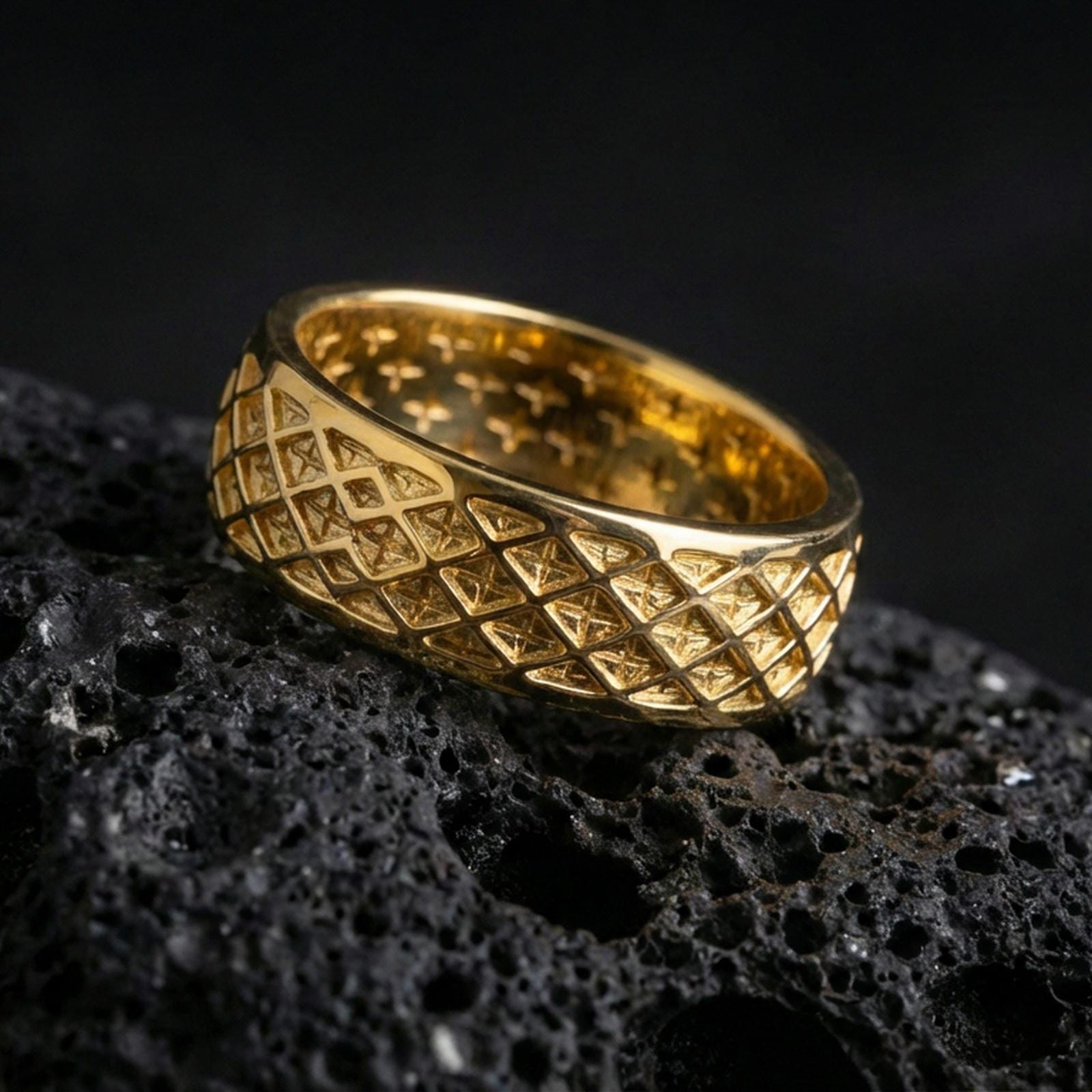 Gold plated geometric lattice band ring on volcanic rock, detailed diamond grid engraving with bold depth, luxury jewelry product photography.