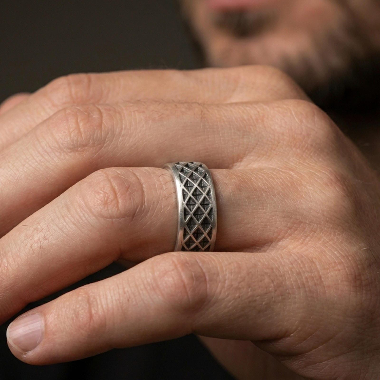 Oxidized sterling silver lattice band worn on finger, diamond grid texture detail, natural lifestyle hand shot with shallow depth of field.
