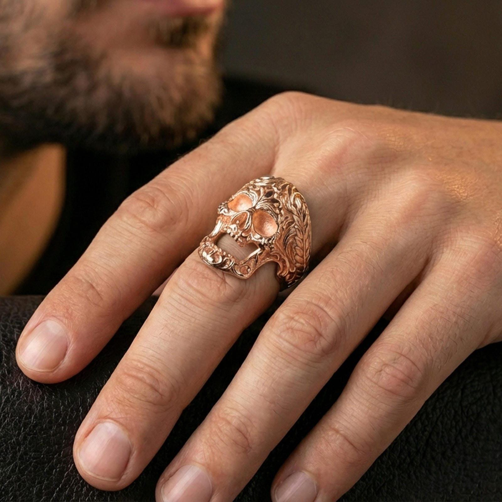 Rose gold plated filigree skull ring worn on a finger, close-up lifestyle photo showcasing warm finish, braided edge detail and sculpted skull face