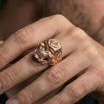 Load image into Gallery viewer, Rose gold plated skull ring with square and compass “G” symbol worn on a finger, close-up lifestyle photo with warm finish and ornate scrollwork detail
